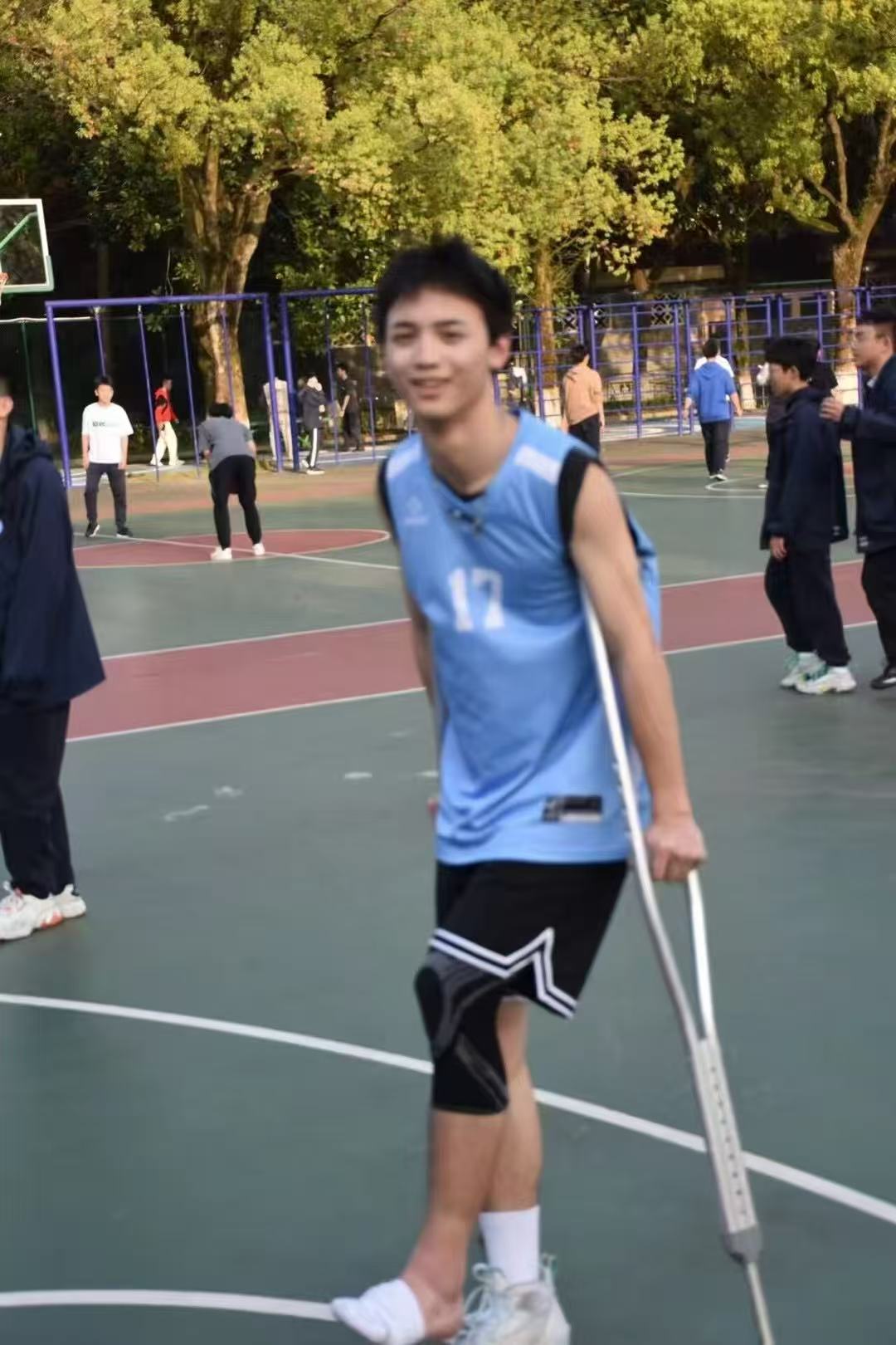 A player in a blue basketball jersey standing with crutches on the court